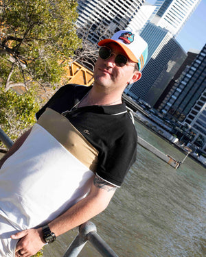 Man wearing sunglasses and a platypus cap with a cityscape and river in the background