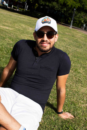 Man wearing a fish cap from OZ Critter and sunglasses sitting on grass