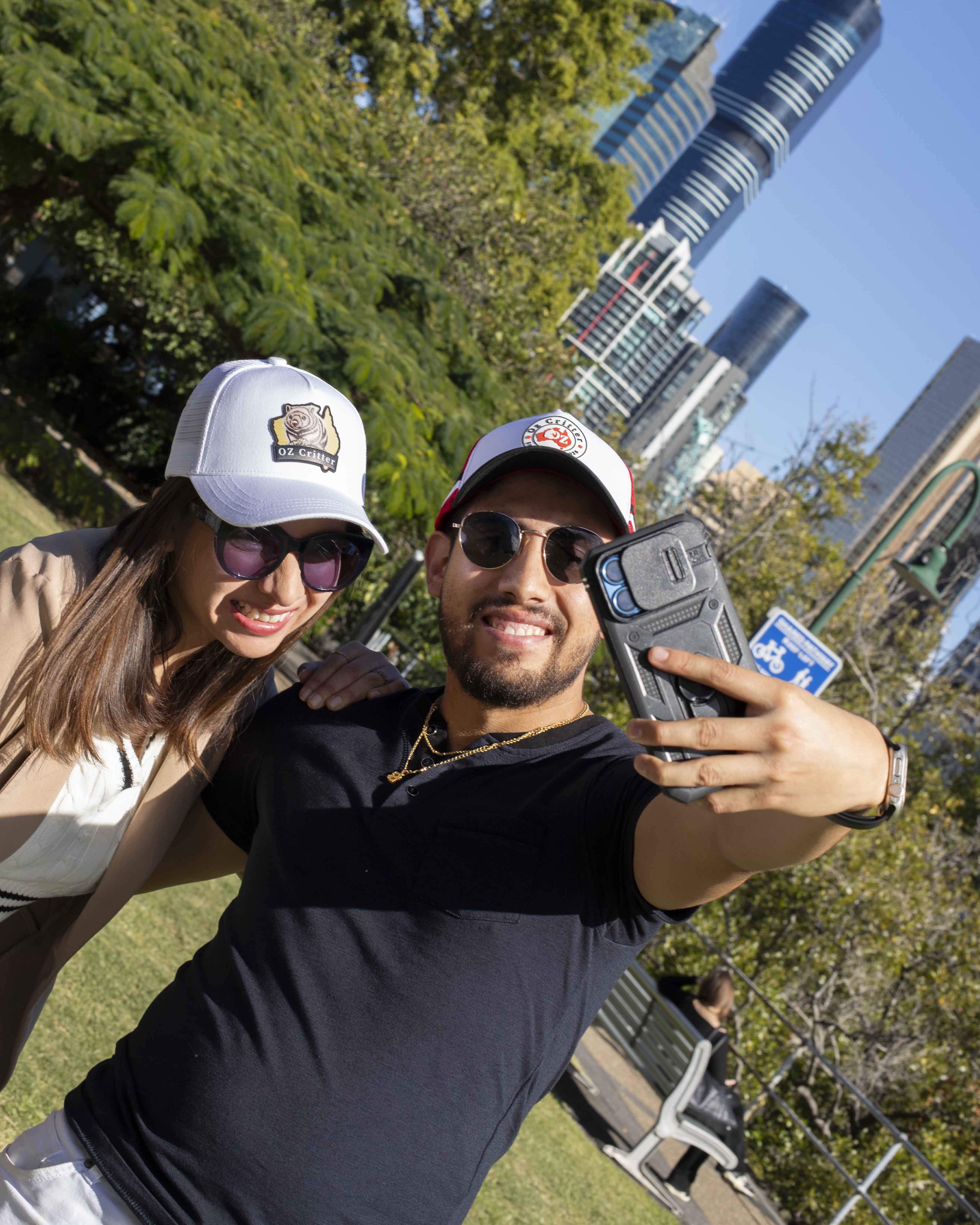 Two people taking a selfie with a cityscape in the background