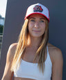 Woman wearing a red and white kangaroo cap, standing against a dark background.