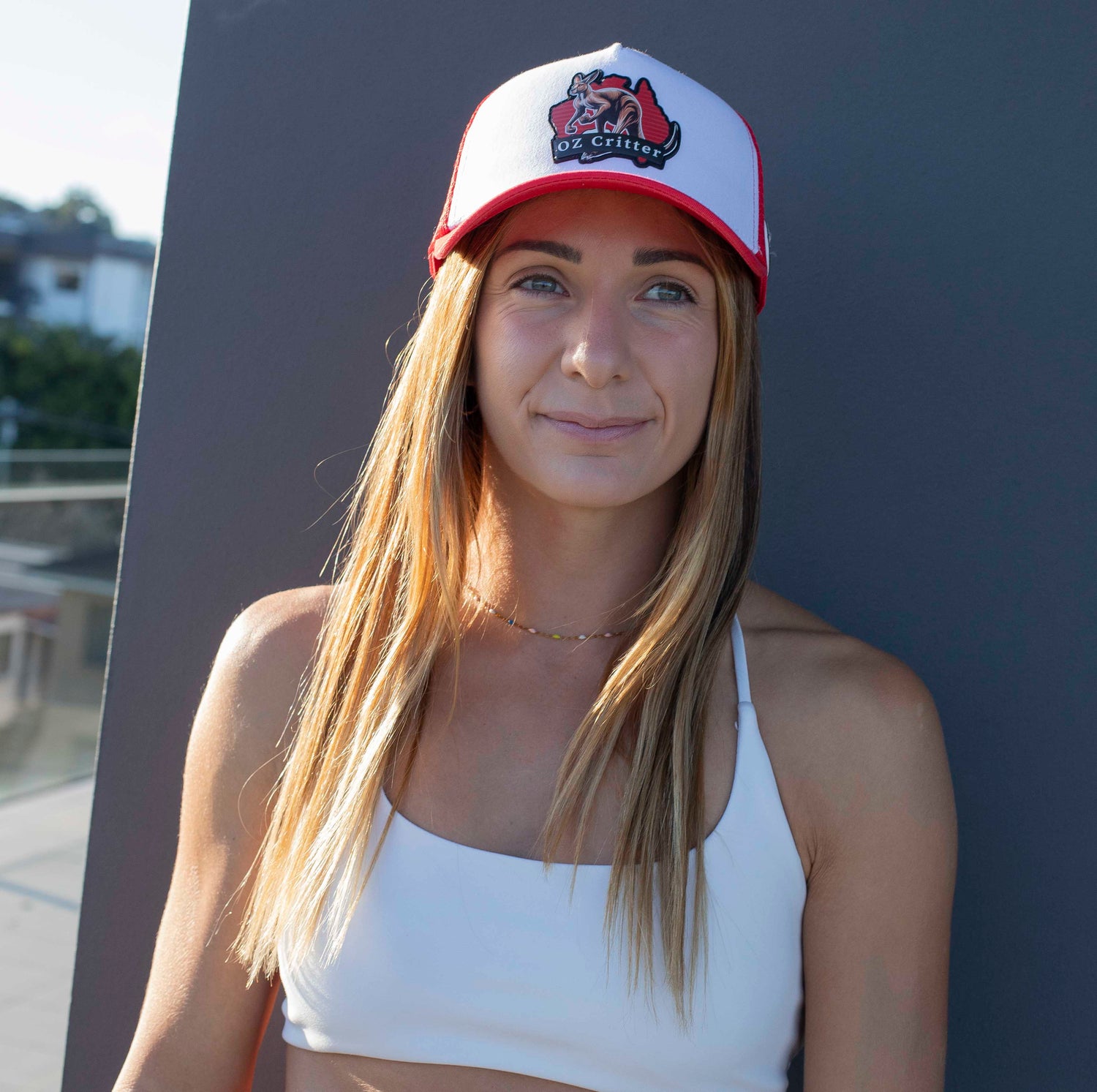 Woman wearing a red and white kangaroo cap, standing against a dark background.