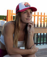 Woman wearing a red and white kangaroo cap, sitting outdoors on a wooden deck.